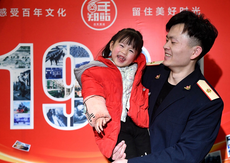 1月21日,一名体验者身穿铁路职工工作服怀抱孩子留影.